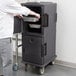 A man using a Cambro Ultra Camcart to hold food in a metal container.