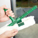 A person holding a Unger green StripWasher with a white handle.