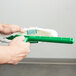 A person holding a Unger green plastic T-bar with a green mop.