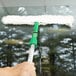 An Unger 18" StripWasher with a green plastic T-Bar cleaning a window.