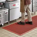 A man standing on a red Choice anti-fatigue floor mat with beveled edges.