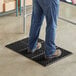 A man standing on a Lavex black rubber anti-fatigue floor mat.