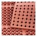 A close up of a red rubber Choice anti-fatigue floor mat with a straight edge and holes in the surface.