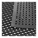 A close-up of a Lavex black rubber anti-fatigue floor mat with holes in it.