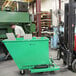 A man using a forklift to move a green Valley Craft mobile hopper.