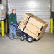 A man pushing a Valley Craft blue hand truck with a large cardboard box.