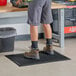 A man standing on a black rubber anti-fatigue floor mat.