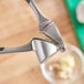 A person using a Choice chrome garlic press to cut garlic.