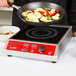 A chef using a Vollrath carbon steel non-stick fry pan to cook vegetables on a stove.