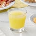 A glass of Dole Pineapple Juice on a table with breakfast food.