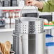 A woman using a Winco aluminum stock pot to steam food.
