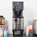 A Grindmaster coffee machine next to cups and other items.
