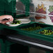 A person using a Cambro Versa food/salad bar to prepare a plate of salad.