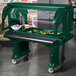 A green Cambro Versa food and salad bar on a table with food buffet trays.