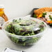 A salad in a Fineline clear plastic bowl with a clear plastic dome lid.