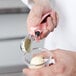 A person using a Vollrath pink squeeze handle scoop to add ice cream to a bowl.