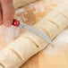 A person using a Victorinox aluminum folding bread lame to score dough.