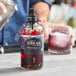 A man using a Rokz Citrus Blueberry Cocktail Infusion Kit to pour a cocktail into a glass.