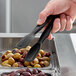 A hand using Cambro black plastic tongs to serve olives.