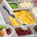 A person wearing gloves uses a Vollrath blue perforated round Spoodle to serve macaroni and cheese from a tray.