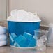 A Lavex disposable paper ice bucket filled with ice cubes next to a plastic cup.