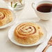 A plate of Bridor cinnamon rolls with a cup of coffee on a table.