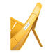 A close up of a yellow Grosfillex Cannes outdoor sidechair with a white label.