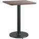 A Lancaster Table & Seating square table with a black metal base and a wooden top on a black pole.