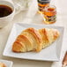 A white plate with a Bridor croissant on it and a cup of coffee.