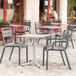 A Grosfillex Cannes charcoal resin outdoor armchair next to a table on a stone patio.