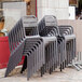 A stack of Grosfillex Cannes charcoal resin outdoor armchairs.