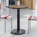 A round standard height table with a reversible birch and ash laminated top and a black cast iron base.