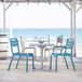 A Grosfillex blue resin outdoor armchair next to a table.