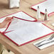 A person holding a burgundy Choice menu cover on a table in an Italian restaurant.