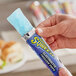 A hand holding a blue Sqwincher sugar free frozen popsicle.