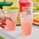 A person holding a glass of Sqwincher Strawberry Lemonade.