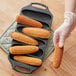 A person using a Lodge 6 slot cast iron cornstick pan to make cornbread in a home kitchen.