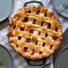 A pie with a lattice top in a Lodge cast iron pie pan with plates on a table.