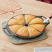 A person cutting cornbread in a Lodge cast iron wedge pan.