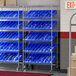 A Regency mobile chrome shelving unit with blue bins on slanted shelves.