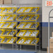 A Regency stationary metal shelving unit with yellow and white bins on it.