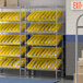 A Regency stationary metal shelving unit with yellow bins on metal slanted shelves.