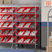 A Regency metal shelving unit with red bins on casters.