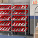 A Regency slanted chrome shelf unit with red bins on it.