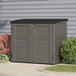 A grey Suncast horizontal storage shed with a black door.