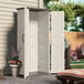 A white Suncast vertical outdoor storage shed with a door.