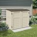 A white Suncast horizontal storage shed with a brown roof in a backyard.