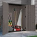 A Suncast Stoney gray vertical storage shed with a lawn mower and other tools inside.