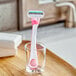 A Gillette Venus Sensitive Disposable Razor in a glass on a counter.