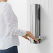 A woman in a white shirt using a Dyson stainless steel ADA compliant hand dryer to open a door.